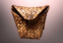     Кошель – короб с крышкой и заплечными лямками, изготовленный из бересты. Среди различных берестяных ёмкостей – корзин, туесов,  бураков кошель занимал особое место. Его использовали для переноски тяжестей за спиной. По сути это берестяной рюкзак,  необходимый рыбакам, охотникам, сборщикам ягод и грибов.  Удобная форма,  лёгкость, водонепроницаемость делали его  незаменимым в каждой крестьянской семье на Русском Севере.  Продукты в таком кошеле не теряли форму, дольше сохранялись  благодаря смолистости  и незначительному  испарению  жидкости  через  поры  бересты. Даже двойной слой бересты даёт хорошую термоизоляцию, что делает кошель ещё и немножко холодильником.   Кошель  прочен,  экологичен и  эргономичен.  Как и в любом изделии в кошеле мастера придерживались принципа         «прочность – польза – красота». Подбирая цветовую гамму  бересты, мастер создавал  настоящие произведения народного искусства.   <br />    Естественно, что  изготовить хороший  кошель не   любому под силу.  Занимались их изготовлением  мастера-кустари.  Это была мужская работа, требующая  физической силы.   Бересту  заготавливали  в начале лета, делая спиральные ленточные срезы со стройных несучковатых берёз.  Бересту  сматывали в клубки и складывали  дома на подпотолочные полки.  Свежая береста более подходила для работы. Для прочности её складывали в несколько слоёв.  В работе использовали кочедык – изогнутое металлическое шило, крюк  для плетения берестяных изделий.  Пересохшую, долго хранившуюся бересту приходилось смачивать водой или маслом.    Одним из известных очагов берестяного промысла в ХIХ – ХХ веке была Авдеевская волость Пудожского уезда.  Мастера из таких  деревень  как Лукостров, Петрушевская Авдеевской волости продавали свои изделия не только в уезде, но и в Петрозаводске. Если за  сезон в  два – три  месяца  кустарь мог заработать  около 16 рублей, то  на ярмарках в Петрозаводске мог выручить  и до   100 рублей за берестяные изделия.                  <br />       Сегодня кошели вышли из употребления и почти не осталось  мастеров, умеющих  их изготавливать.  В Пудожском районе в пос. Пудожгорский  живёт и работает мастер по бересте  Беляй Игорь Владимирович. <br />(Зиновьева Е.В.)<br />